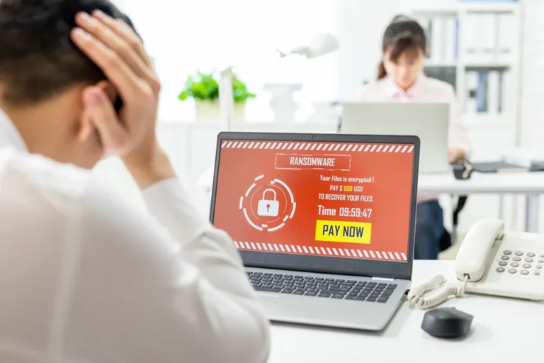 a guy in front of his computer stressed while staring at his computer being attacked by ransomware